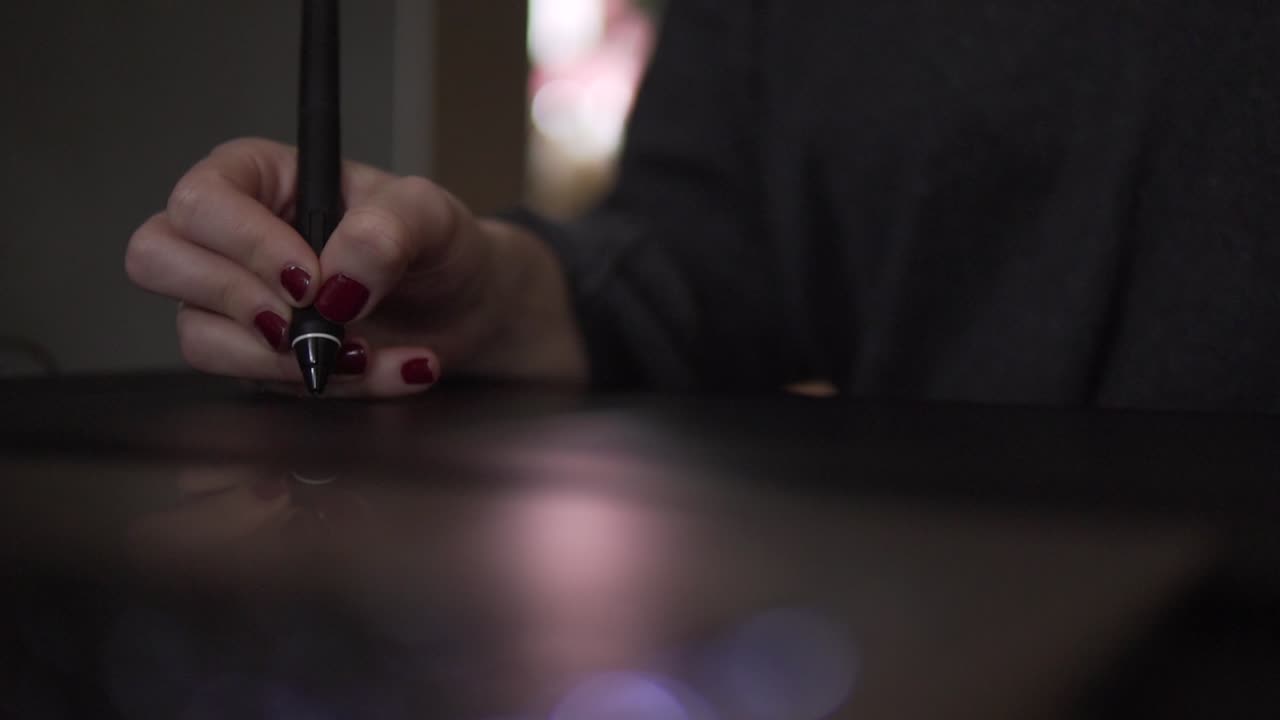 SLOW MOTION: Primo piano della mano di una donna con penna digitale su tavoletta grafica.