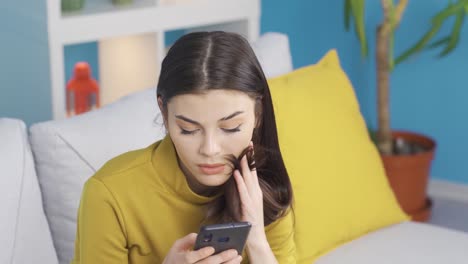 Beautiful-hammering-young-woman-sitting-on-sofa-at-home-looking-at-her-phone,-texting.