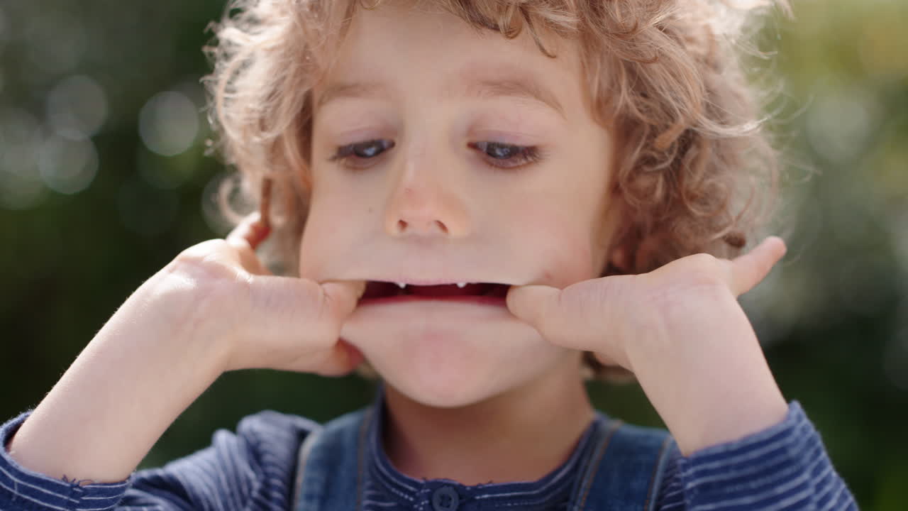 ritratto divertente piccolo ragazzo che fa le facce divertendosi bambino che si diverte a fare espressioni sciocche in sunny park 4k