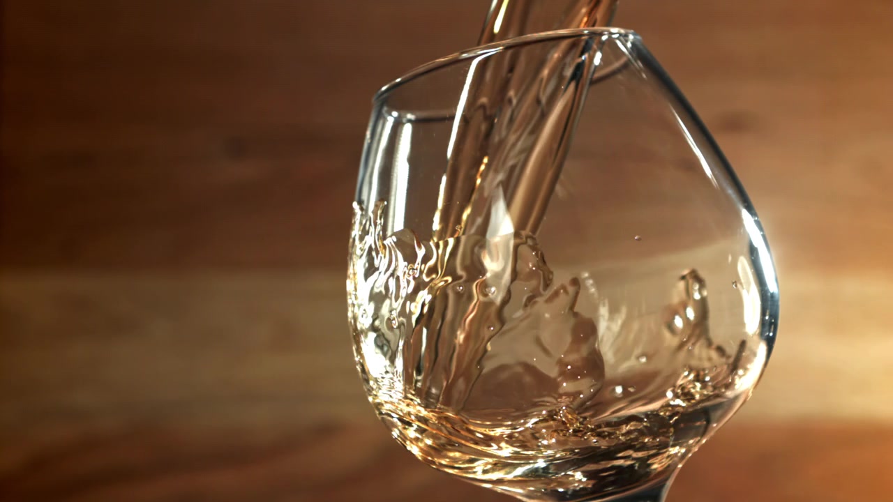 Versamento al rallentatore di vino dorato in un bicchiere