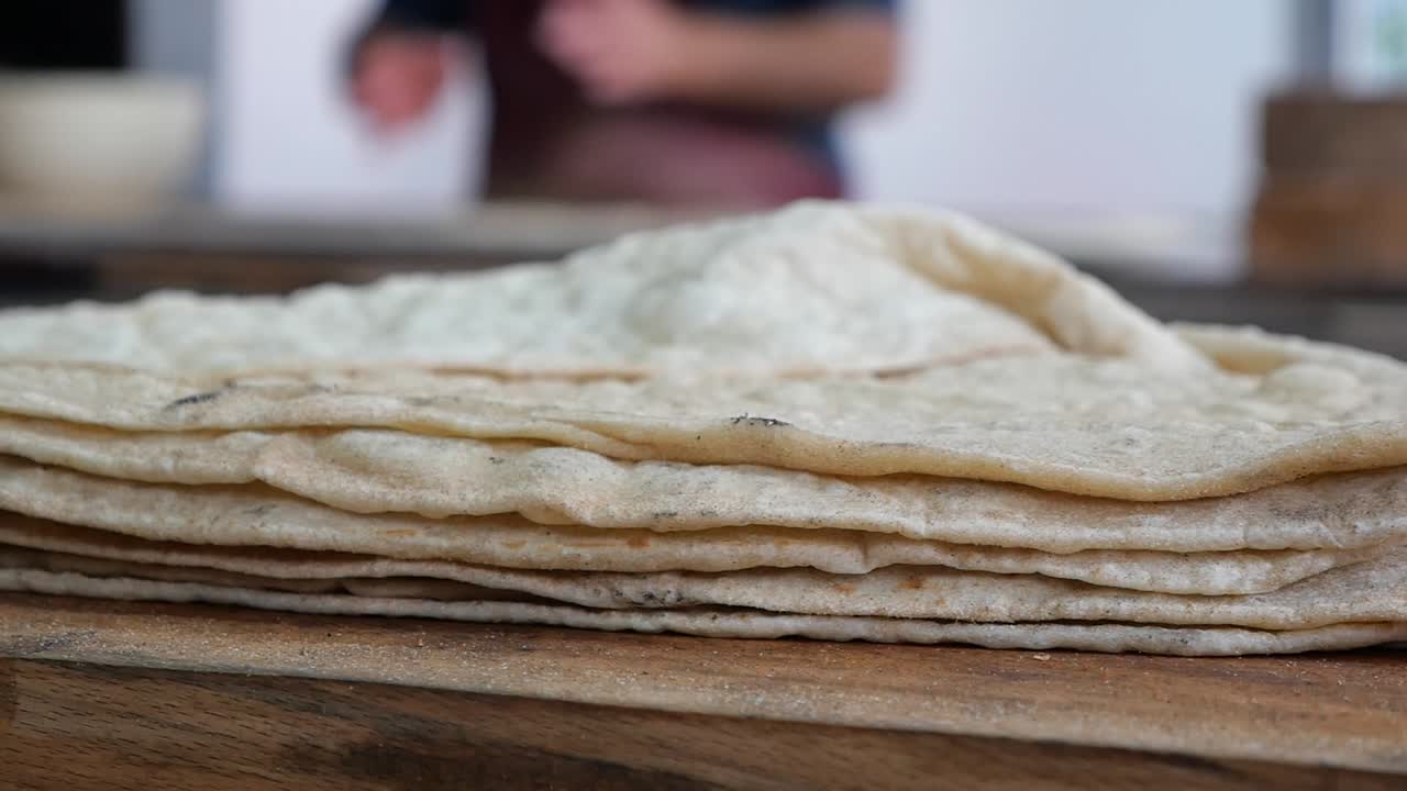 Stabel med nybakt flatbrød på et trebord.