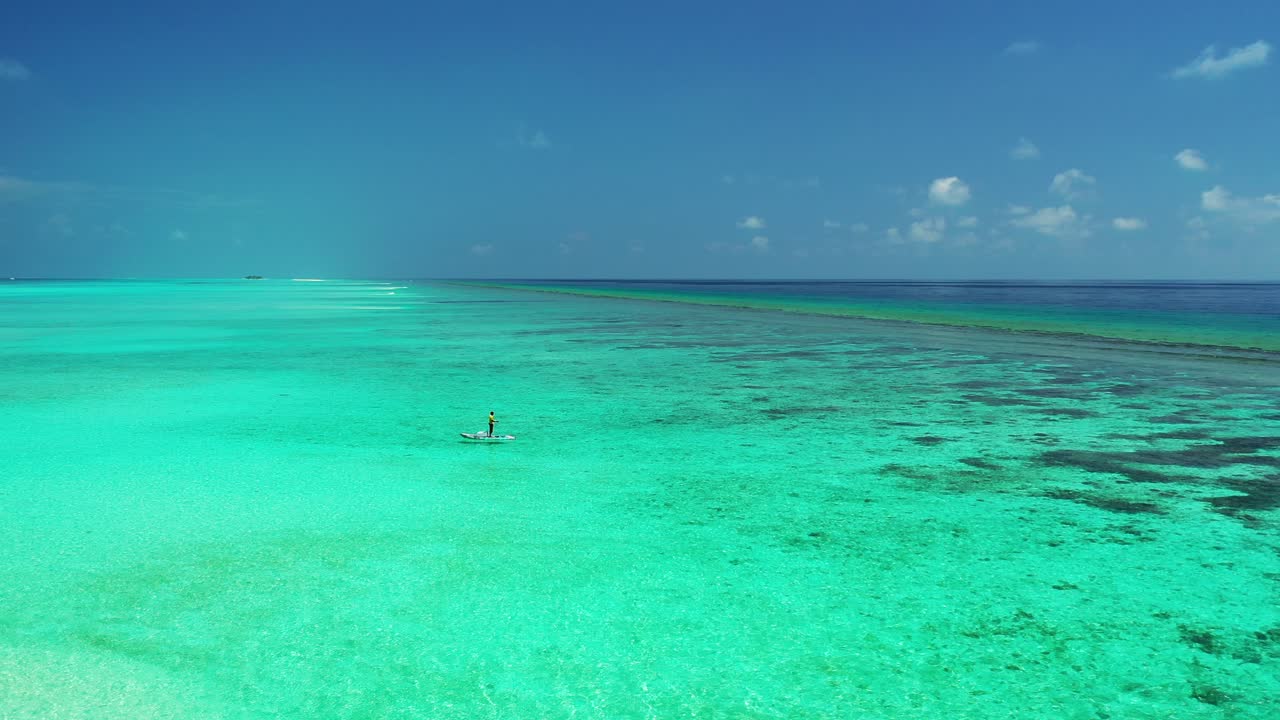 Local fisherman on the paddleboard throwing the fishing line in the calm sea, Maldives