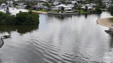 Drone footage captures serene canal-side luxury homes in Gold Coast, Australia, under soft daylight with calm water reflections