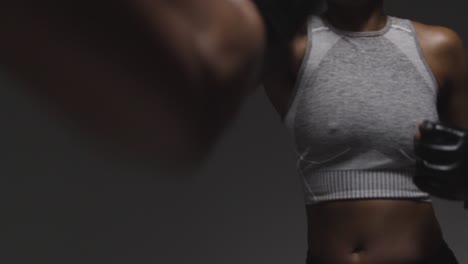 Close-Up-Studio-Shot-Of-Woman-Wearing-Boxing-Gloves-Sparring-With-Trainer