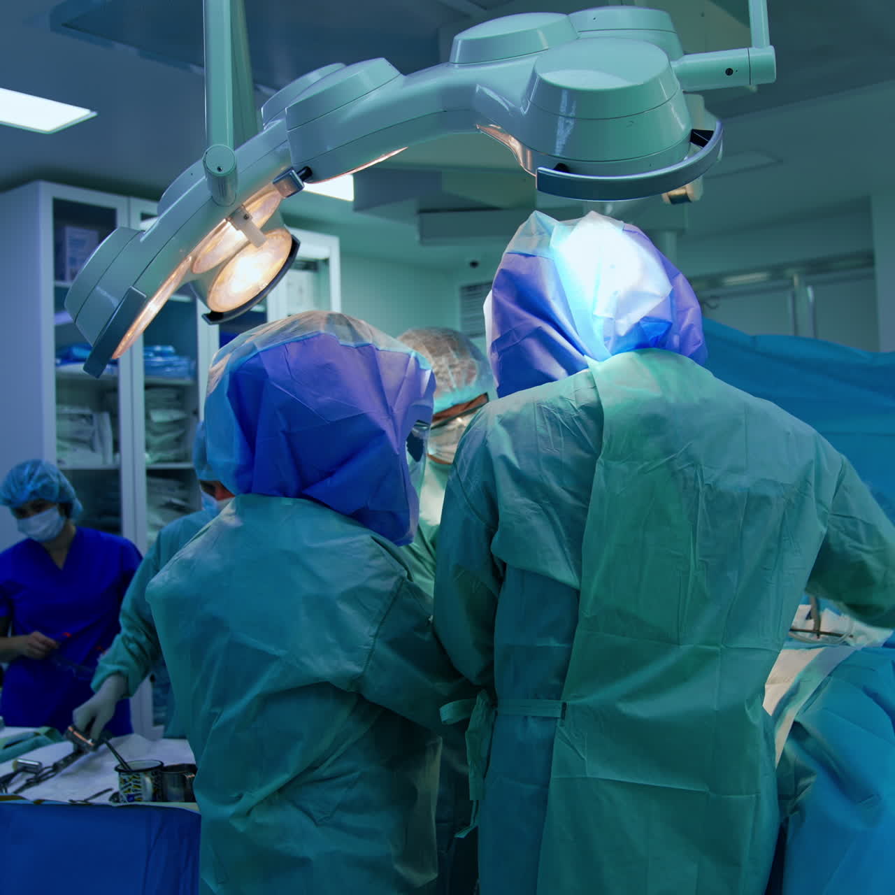 Un team medico lavora al tavolo operatorio. Un assistente maschio prepara gli strumenti per i medici.