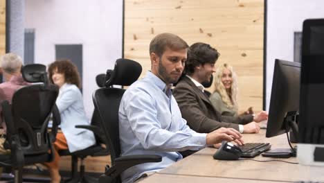 Businessman using computer with colleagues talking in background