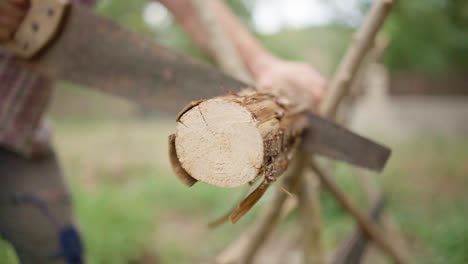 man sawing wood with a hand saw