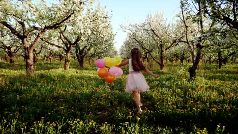 happy girl with balloons running in the garden