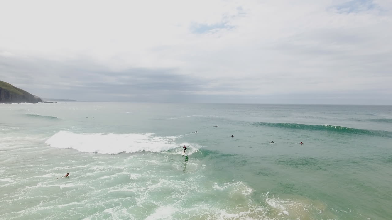 Cinematic flying of surfers surfing along coast of East London South Africa aerial
