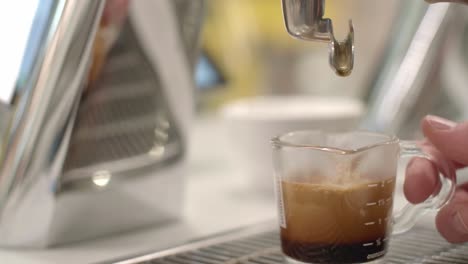 last drip of coffee drops into cup and cafe worker pulls it away, closeup