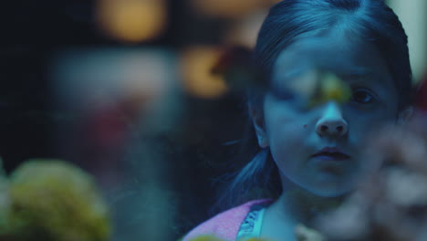 cute little girl in aquarium looking at fish curious child watching colorful sea life swimming in tank learning about marine animals in underwater ecosystem inquisitive kid at oceanarium