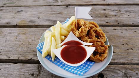 anillo de cebolla y papas fritas con ketchup dispuestas en un plato