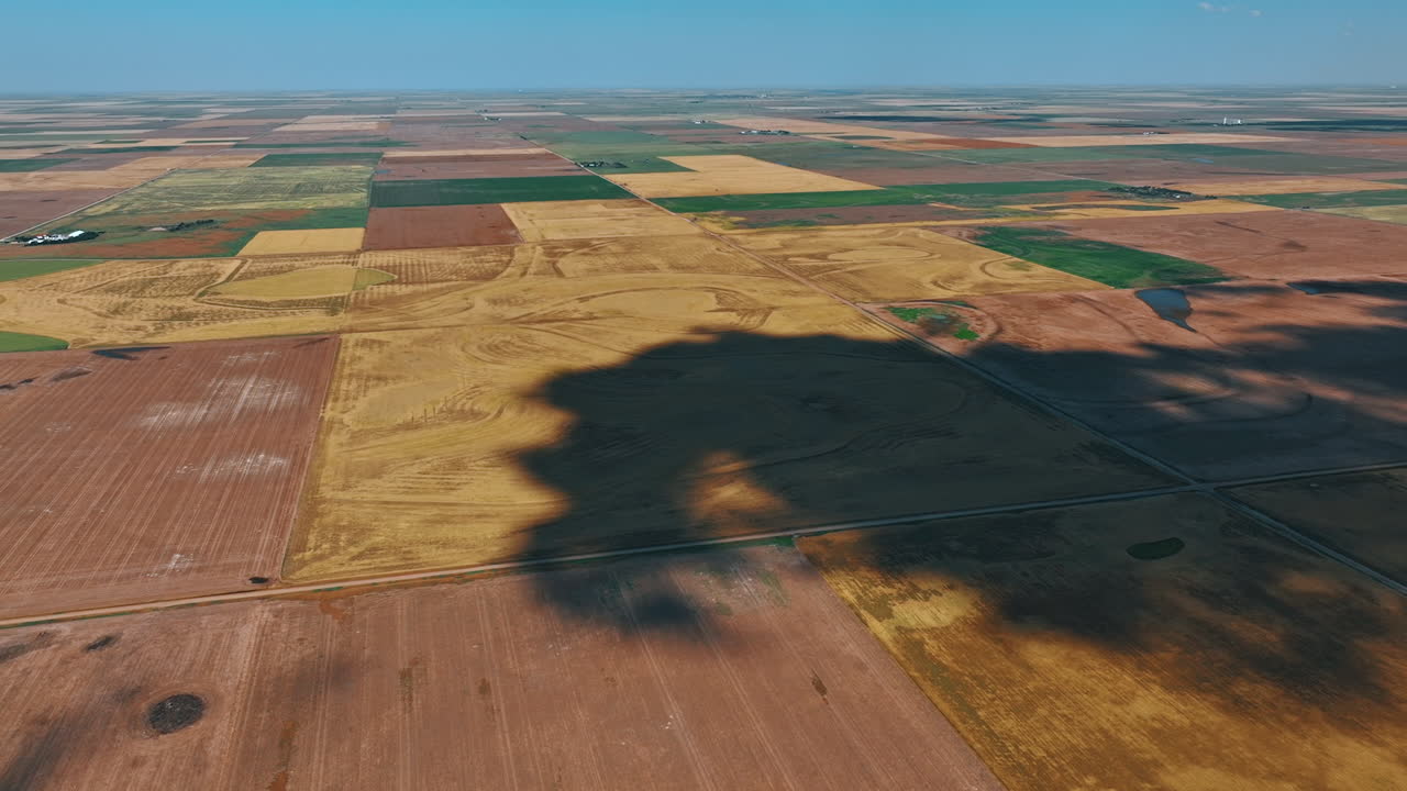 Big shadow from cloud spreads by the ground. Vast territory divided into the fields for agriculture. Top view.