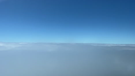 A-pilot’s-perspective-recorded-from-a-jet-cockpit-flying-just-some-layers-of-clouds-during-the-descend-to-Funchal-airpor,-Madeira