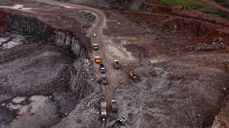 Large equipment working in industrial granite quarry near a road