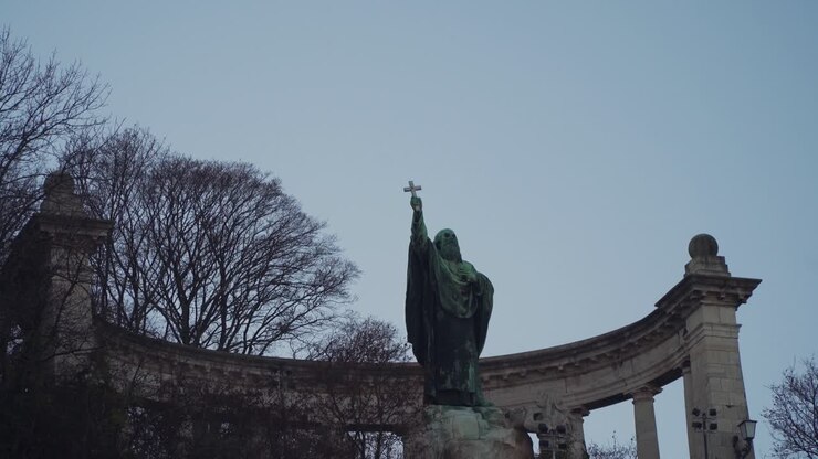 Sankt Gellert-monumentet ved Gellert-højen i Budapest, Ungarn, med nøgne træer og antikke søjler i baggrunden - Tilt-ned panoreringsskud
