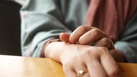 close up of a woman's hand with red nail polish and a gold ring