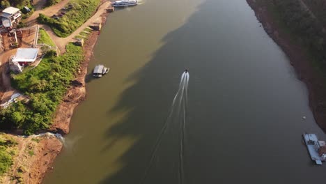 A-dynamic-tracking-shot-of-a-fast-moving-speed-boat-cruising-by-the-Iguazu-river,-border-between-Argentina-and-Brazil