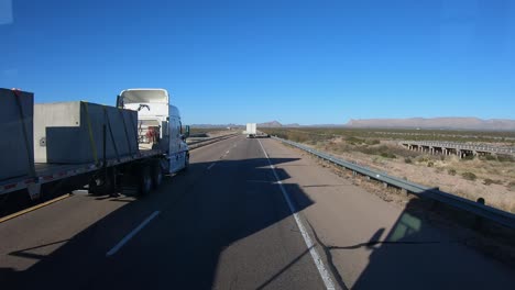 pov while driving along the interstate and passed by two tractor trailers in western texas in a sunny day