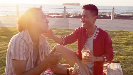 happy diverse gay male couple having picnic at promenade by the sea, slow motion