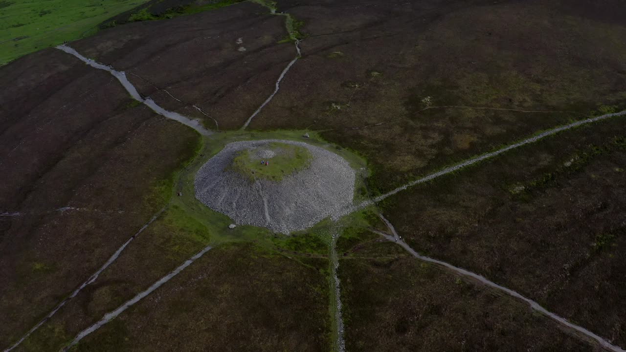 Knocknarea, Coolera peninsula, Sligo, Ireland, June 2021. Drone slowly orbits Queen Meave's Grave at the summit, tilting up to reveal a northern vista of Sligo Bay with Benbulbin in the distance.