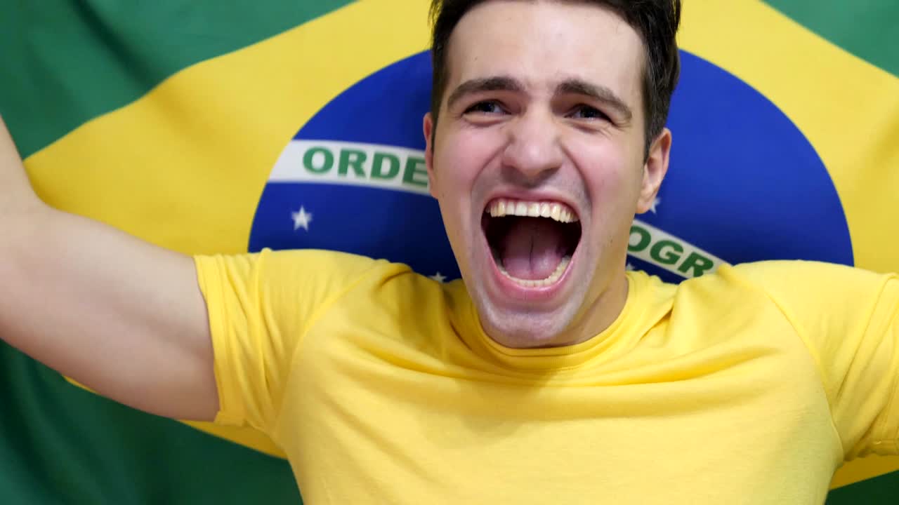 un joven brasileño celebra sosteniendo la bandera de brasil en cámara lenta