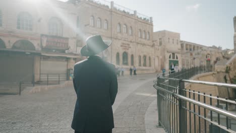 sunlight on an orthodox jew walking beside bars on a steep slope in the old city of jerusalem, israel