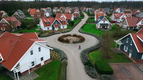 Kind-Fährt-Mit-Dem-Fahrrad-In-Einem-Luxuriösen-Bungalowpark-Aus-Der-Luft,-Von-Oben,-Und-Bewegt-Sich-Vorwärts