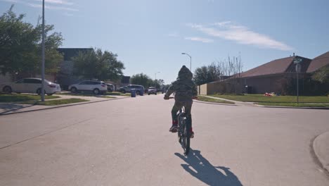 a boy rides his bike through his neighborhood at regular speed in 4k