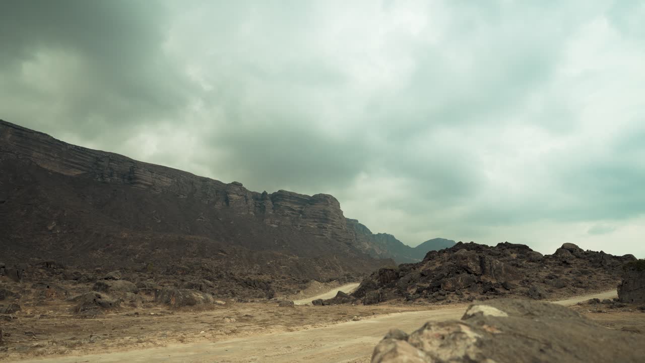 Dirt roads through the rugged mountains of Oman near Yemen - overcast, gloomy desert landscape