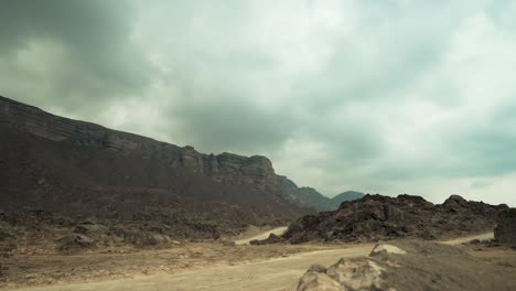dirt roads through the rugged mountains of oman near yemen - overcast, gloomy desert landscape