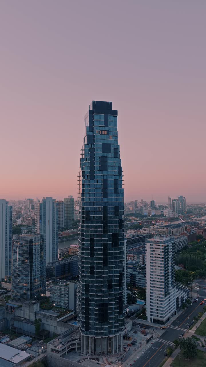 Ripresa drone semi-orbitale verticale attorno al grattacielo Harbour Tower a Puerto Madero durante il tramonto, architettura residenziale moderna con calda luce serale a Buenos Aires