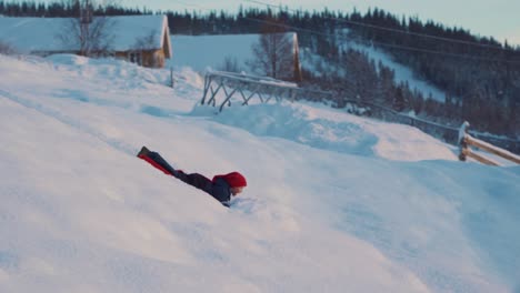 foto de un niño pequeño divirtiéndose en la nieve, disfrutando de los placeres de andar en trineo usando un trineo de pala de plástico rojo en beitostolen, pueblo en el municipio de oystre slidre en el condado de innlandet, beito, noruega