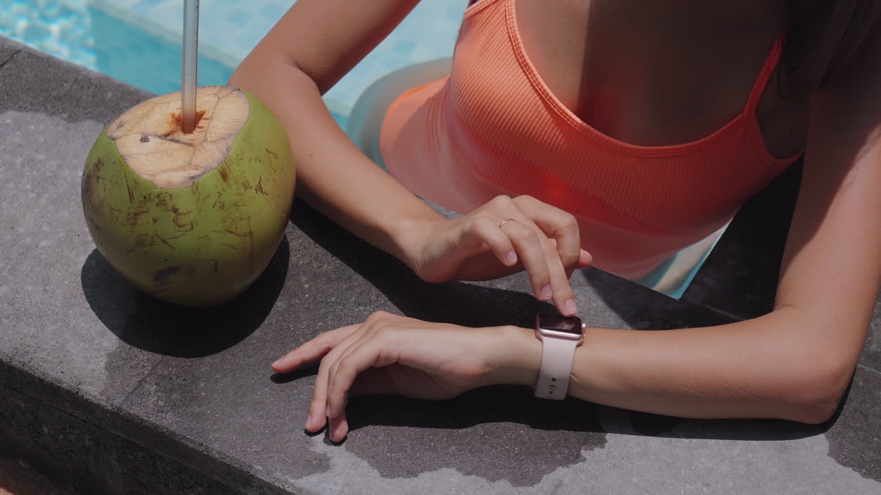 Woman relaxing by the pool with a coconut drink