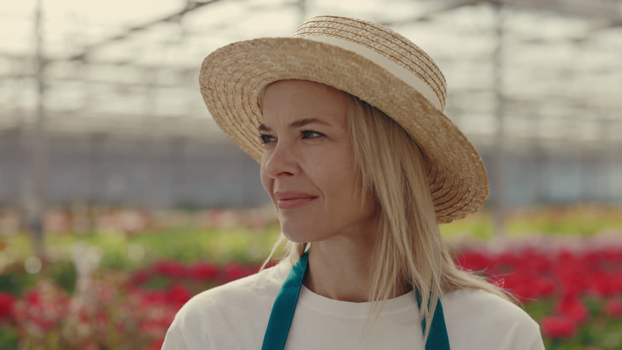 Smiling Woman in Straw Hat in a Greenhouse