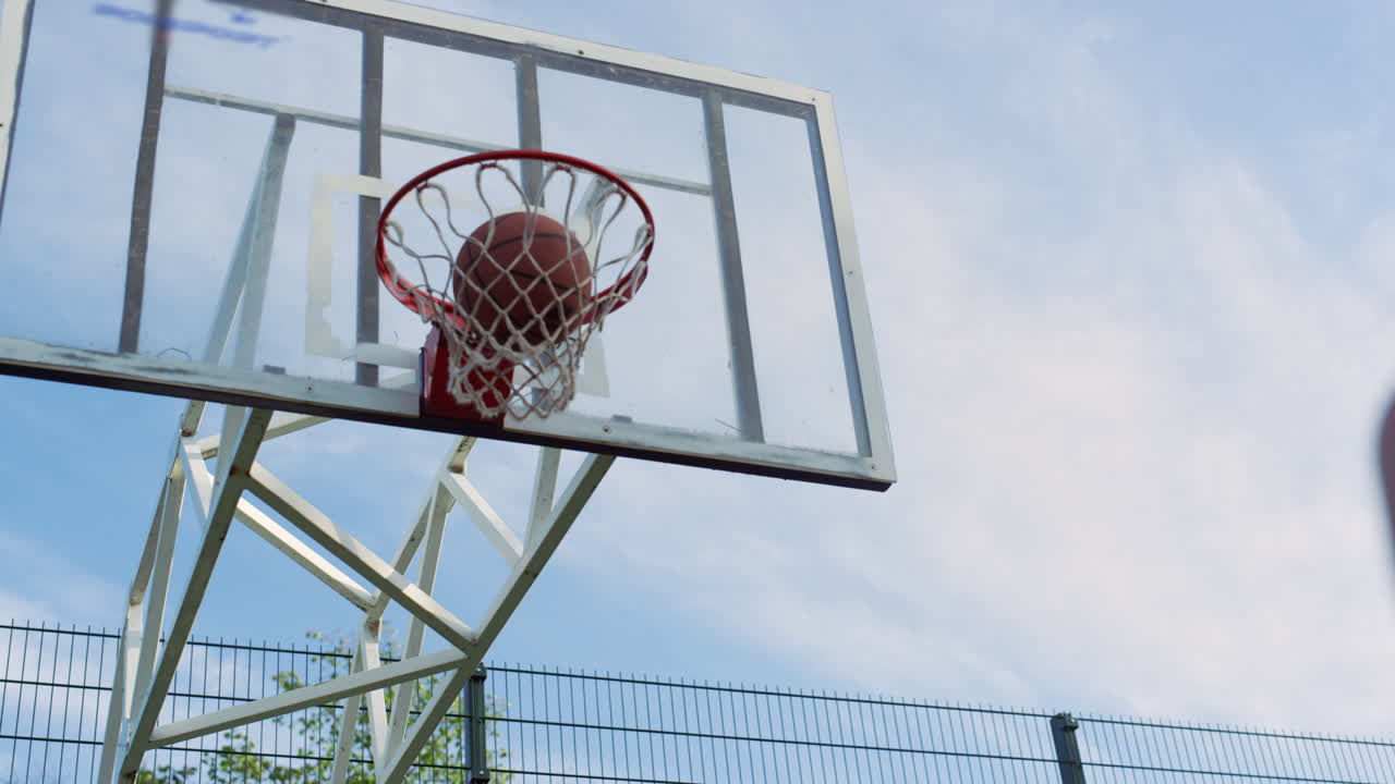 mujer deportiva concentrada practicando baloncesto callejero con un hombre en el patio de recreo.