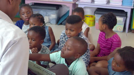 teacher holds a book for elementary school children to read