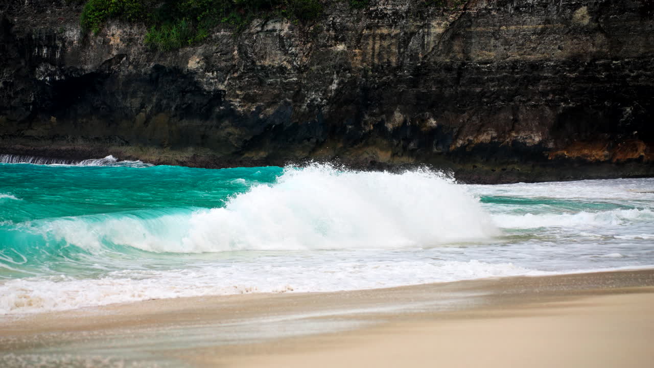 Onde scenografiche che si infrangono sulla costa sabbiosa a Bali, Indonesia