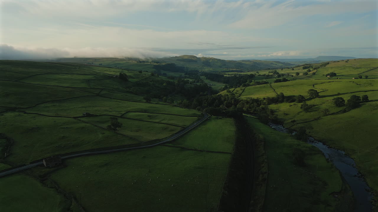 Fremadrettet droneoptagelse over Yorkshire Dales' bakker og marker ved den gyldne time.