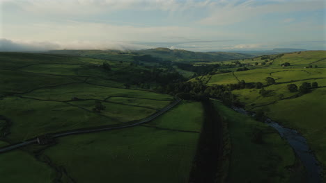 establishing drone shot forward over yorkshire dales hills and fields at golden hour