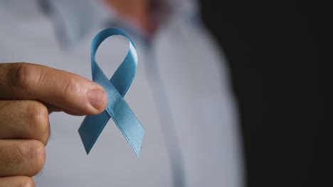 Close Up Of Man Holding Blue Ribbon Badge Symbolizing Awareness Of Men&#039;s Health And Cancer 1