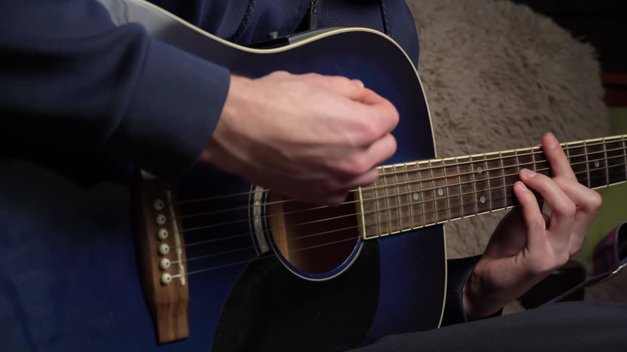 hombre toca una pica en una guitarra moderna en la oscuridad