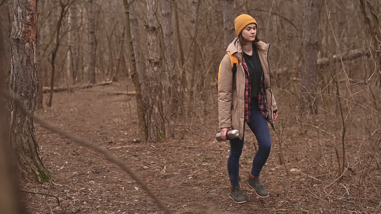 A Young Girl In A Yellow Woolen Hat Walks Through The Forest