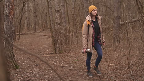 uma jovem com um chapéu de lã amarelo caminha pela floresta