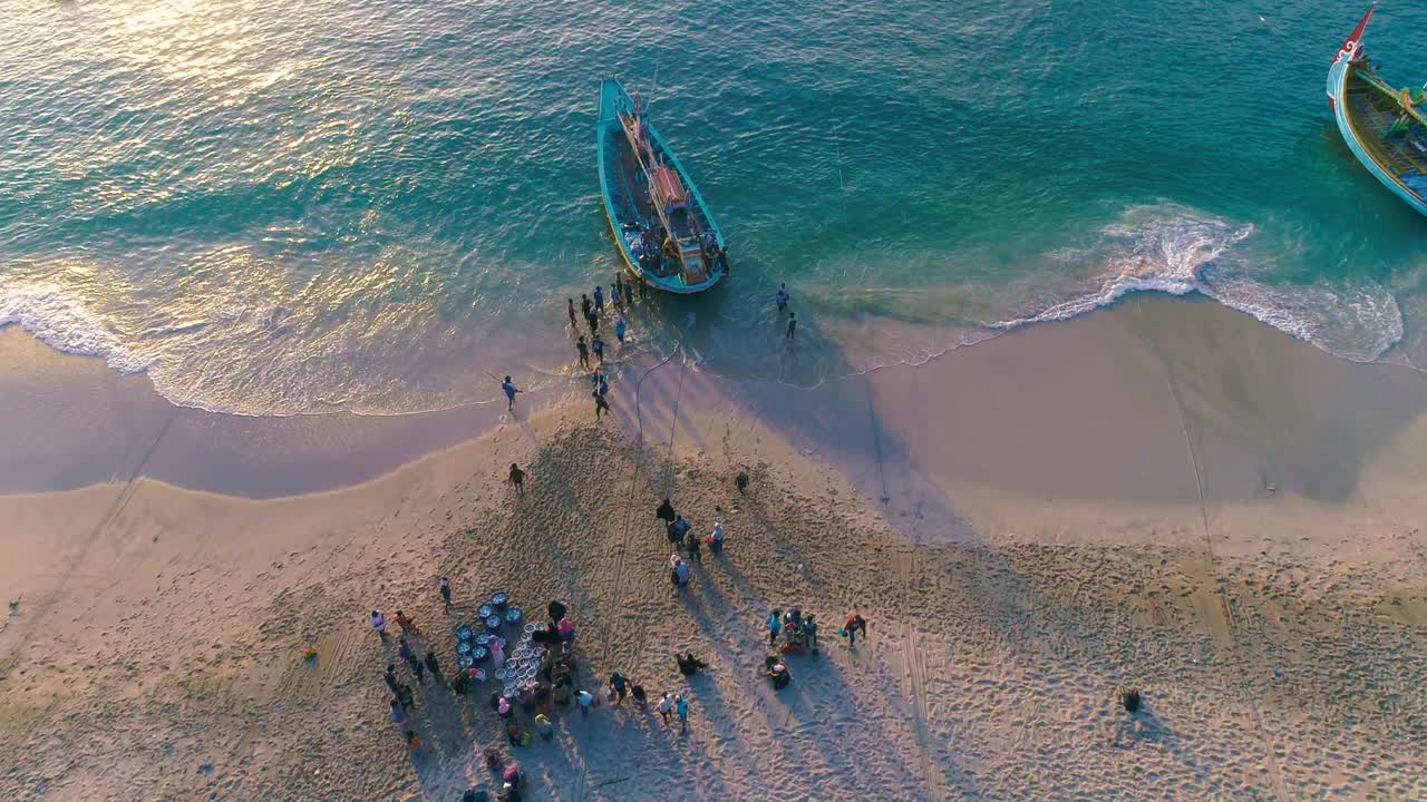 지역 어부들이 해가 뜨면 배에서 잡은 물고기를 해변으로 내리는 모습 (공중에서 볼 수 있는 사진, 인도네시아)
