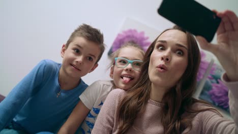 familia feliz tomando selfie móvil. madre hermosa con los niños tomando foto móvil