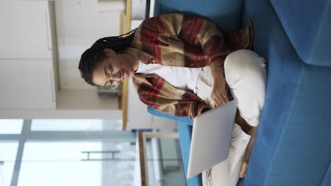 Woman-with-dreadlocks-is-working-using-laptop-on-couch,-communication-concept