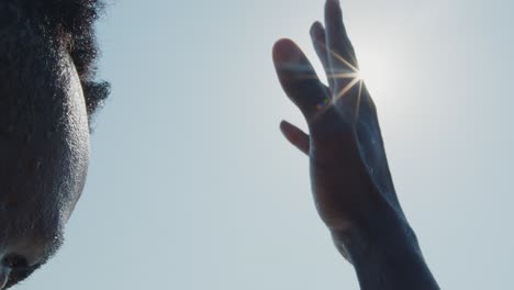 la mano de una persona negra girando en el aire contra los brillantes rayos del sol
