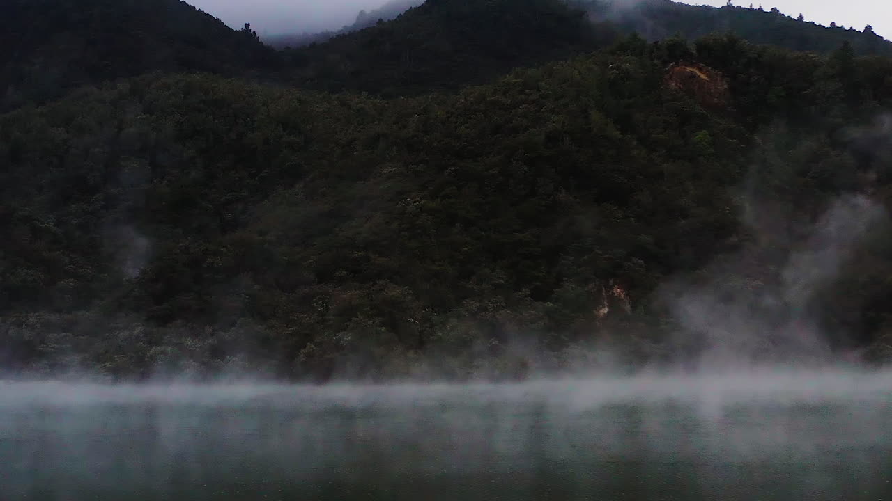 Zoom in on steam rising from geothermal lake in volcanic region, New Zealand, North Island