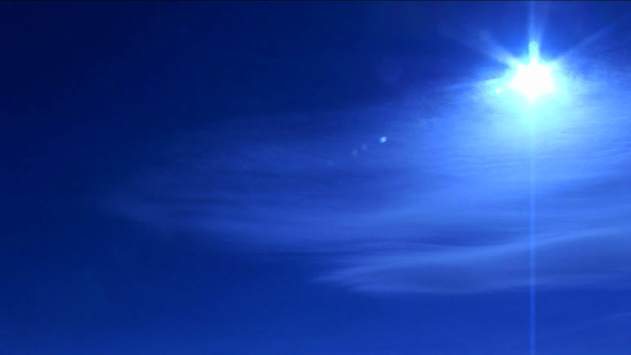 푸른 빛으로 구름에 대해 빛나는 태양